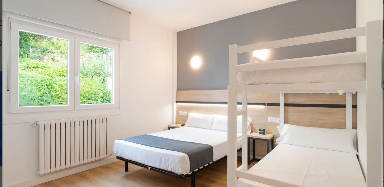 Een slaapkamer met twee bedden, een raam en een radiator.