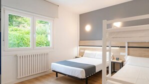 Un dormitorio con dos camas, una ventana, un radiador y una mesita de noche.