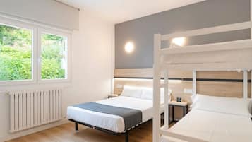 Een slaapkamer met twee bedden, een raam en een radiator.