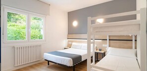 Un dormitorio con dos camas, una ventana, un radiador y una mesita de noche.