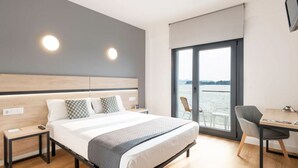 Una habitación de hotel moderna con una cama grande, un escritorio y vistas al agua.