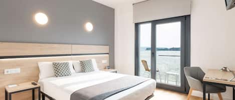 Una habitación de hotel moderna con una cama grande, un escritorio y vistas al agua.