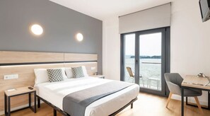 Una habitación de hotel moderna con una cama grande, un escritorio y vistas al agua.