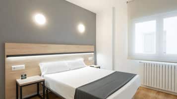 Habitación de hotel moderna con cama, mesita de noche y ventana con persianas.
