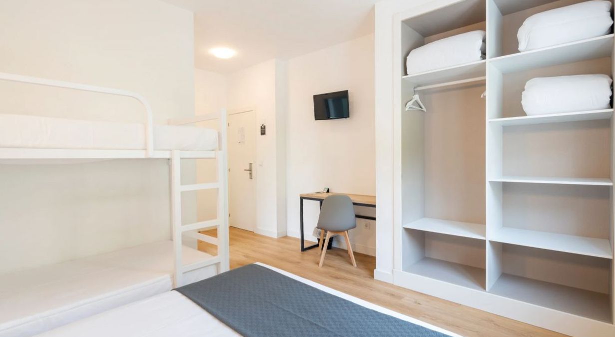 Una habitación con literas, un escritorio, una silla y un armario grande.