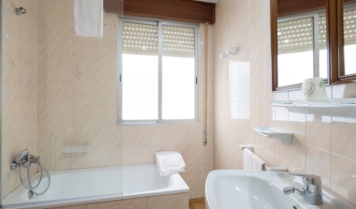 Ein modernes Badezimmer mit Badewanne, Waschbecken und einem Fenster mit Jalousien.
