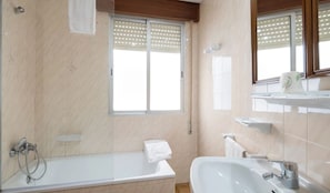 Une salle de bain moderne avec une baignoire, un lavabo et une fenêtre équipée de stores.