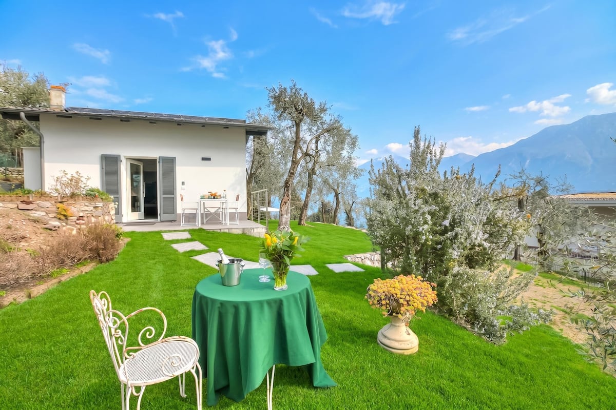 Une maison moderne avec une pelouse bien entretenue, une table à manger avec des chaises et une vue sur les montagnes.