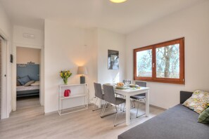 Un espace de vie compact comprenant un coin repas, un canapé, une fenêtre avec vue et une petite kitchenette.