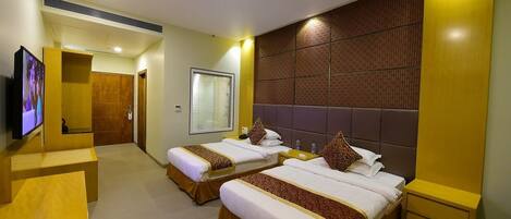 A hotel room with two beds, a TV, a desk, and a bathroom.