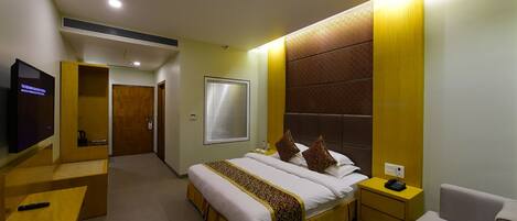 A hotel room with a large bed, bedside tables, a TV, and a seating area.
