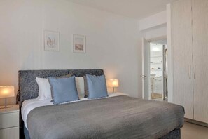 Relax in a serene bedroom with a large bed, framed artworks, and a stylish wardrobe.