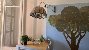 A dining area with a table set for four, a wall-mounted lamp, and a mural of a tree with oranges.