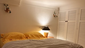 A bedroom with a bed, a bedside lamp, and a wardrobe.