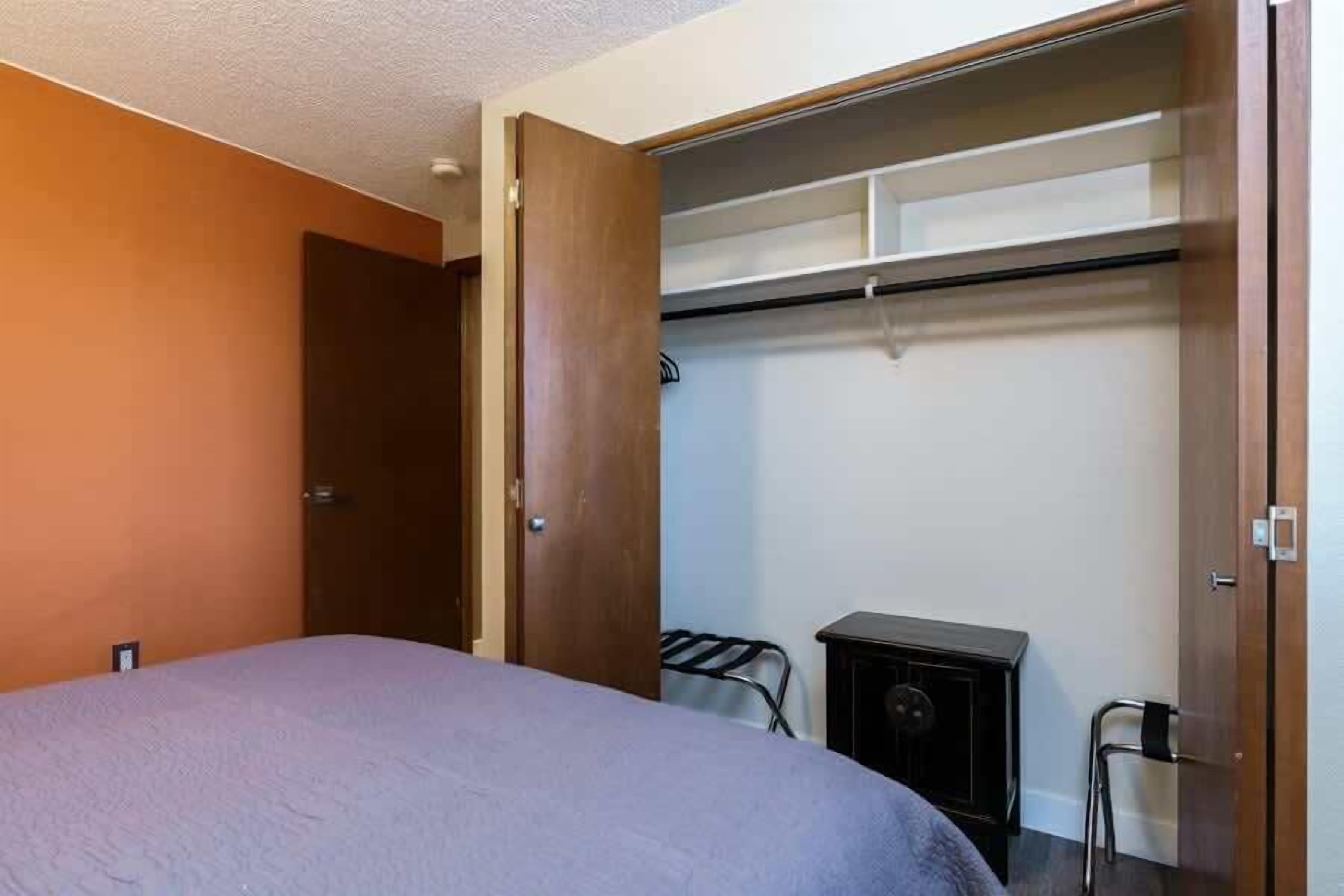 A hotel room with a bed, a wardrobe, and a small table with a chair.