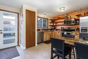 A compact kitchen with wooden cabinets, a built-in microwave, and a stainless steel refrigerator. - #StayInMyDistrict Furnished Monthly Rental Boise (Boise)