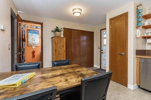 A dining area with a wooden table, four chairs, a cabinet, and a door with a sign. - #StayInMyDistrict Furnished Monthly Rental Boise (Boise)