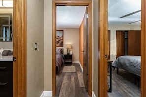 A narrow hallway leading to a bedroom with a bed, a nightstand, and a lamp. - #StayInMyDistrict Furnished Monthly Rental Boise (Boise)