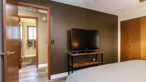 Une chambre à coucher avec un lit, un téléviseur posé sur un meuble en bois et une armoire.