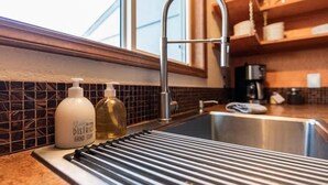 Une cuisine équipée d’un évier en acier inoxydable, d’un robinet et de deux flacons de savon liquide placés sur le comptoir.