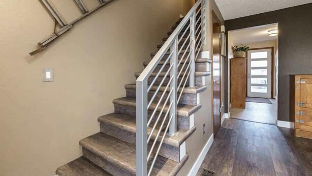 Un escalier avec une rampe en métal, des marches en bois et un plancher foncé.
