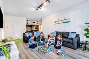 A modern living room with a sofa, a dining table, and a kitchen area in the background.