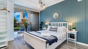 A bedroom with a bed, bedside tables, a mirror, and a view of a balcony. - `Family Beach Getaway` by Inn Paradise (Surfers Paradise)