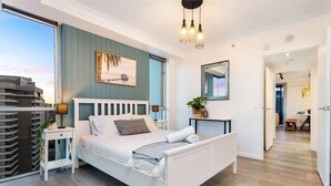 A bedroom with a bed, bedside tables, a nightstand, a mirror, and a view of the cityscape. - `Boutique Sky Villa` by Inn Paradise (Surfers Paradise)