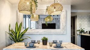 A dining area with a rustic wooden table, hanging woven light fixtures, and a large window with a view of the city. - `Boutique Sky Villa` by Inn Paradise (Surfers Paradise)