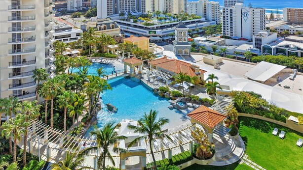 A resort with a large swimming pool, palm trees, and high-rise buildings in the background. - `Boutique Sky Villa` by Inn Paradise (Surfers Paradise)