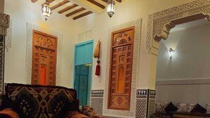 A traditional Moroccan interior with a patterned floor, ornate doors, and a sofa with cushions. - Fez Experience (Fes)