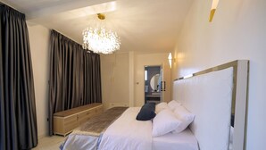 A bedroom with a bed, bedside table, and a hanging light fixture. - EL AMO LAKEVIEW VILLA (Entebbe)