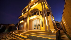 A modern building with a prominent entrance, multiple floors, and a staircase leading to the entrance. - EL AMO LAKEVIEW VILLA (Entebbe)