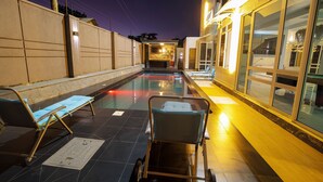 A swimming pool with lounge chairs and a view of the building's interior. - EL AMO LAKEVIEW VILLA (Entebbe)