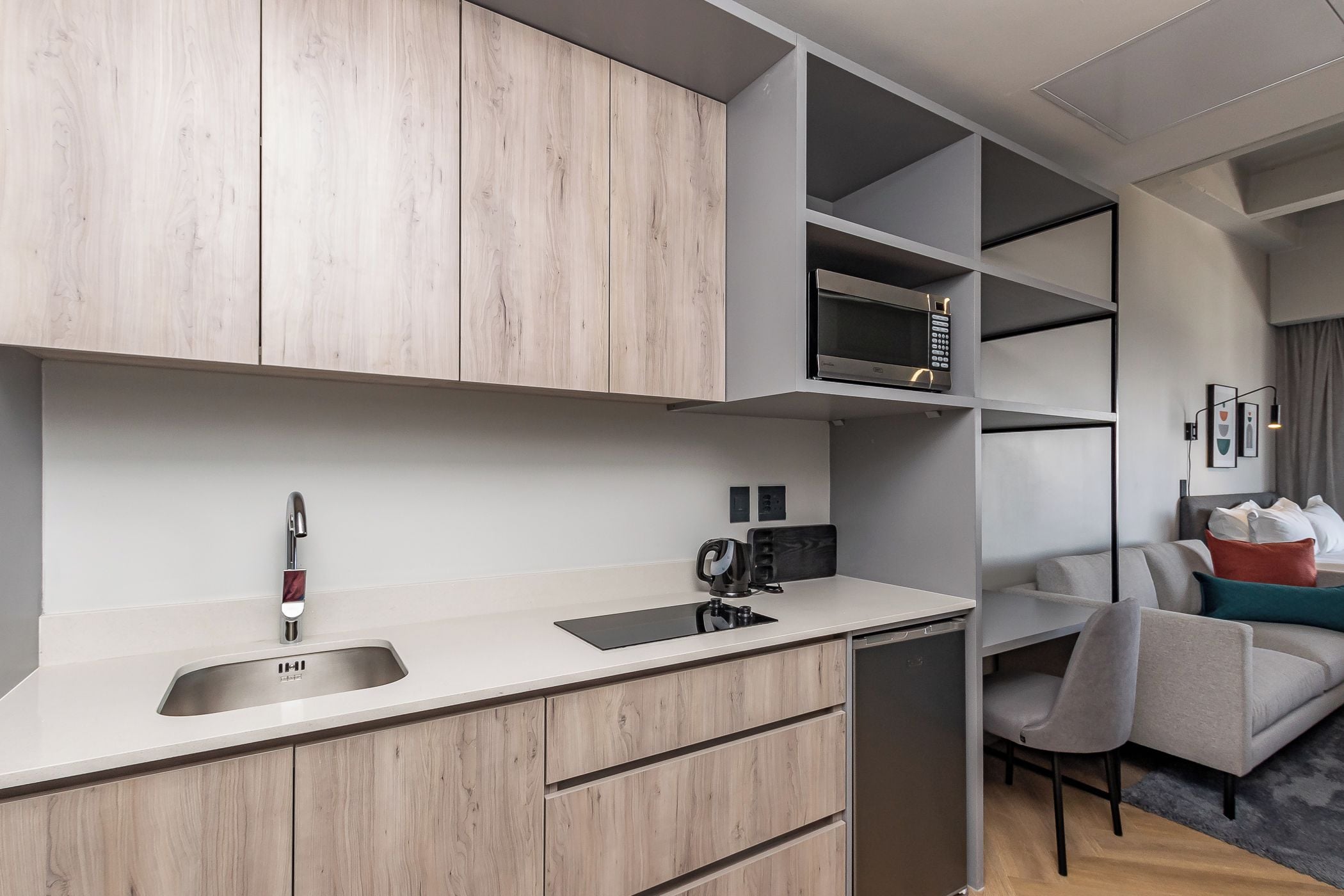 A modern kitchenette with a built-in microwave, a sink, and a coffee machine.