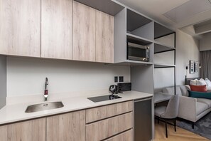 A modern kitchenette with a built-in microwave, a sink, and a coffee machine. - One Thibault Residence By Itc Hospitality (Cape Town)