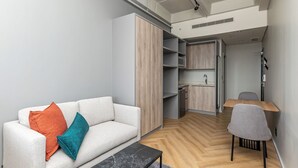 A modern living room with a sofa, a coffee table, and a dining area with a table and chairs. - One Thibault Residence By Itc Hospitality (Cape Town)