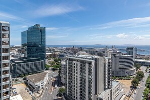 A high-rise building with a glass facade, surrounded by other buildings and a clear sky. - One Thibault Residence By Itc Hospitality (Cape Town)