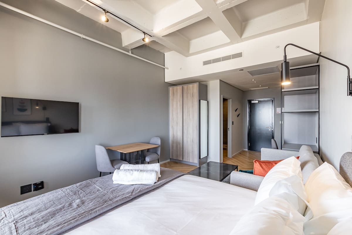A modern hotel room with a large bed, a desk, and a TV.
