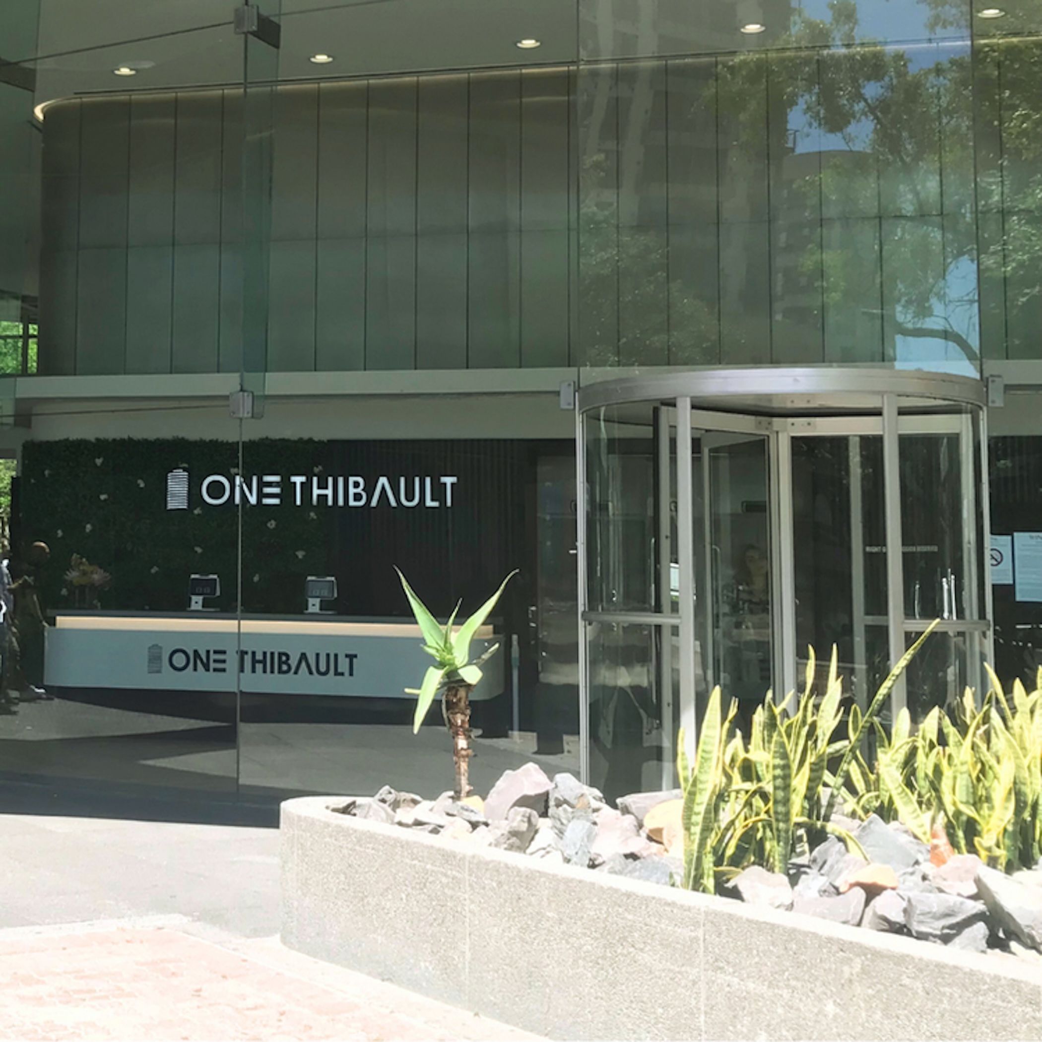 A modern building with a glass facade and a revolving door entrance.