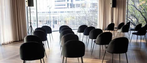 A conference room with rows of black chairs, a table, and a speaker on a tripod.