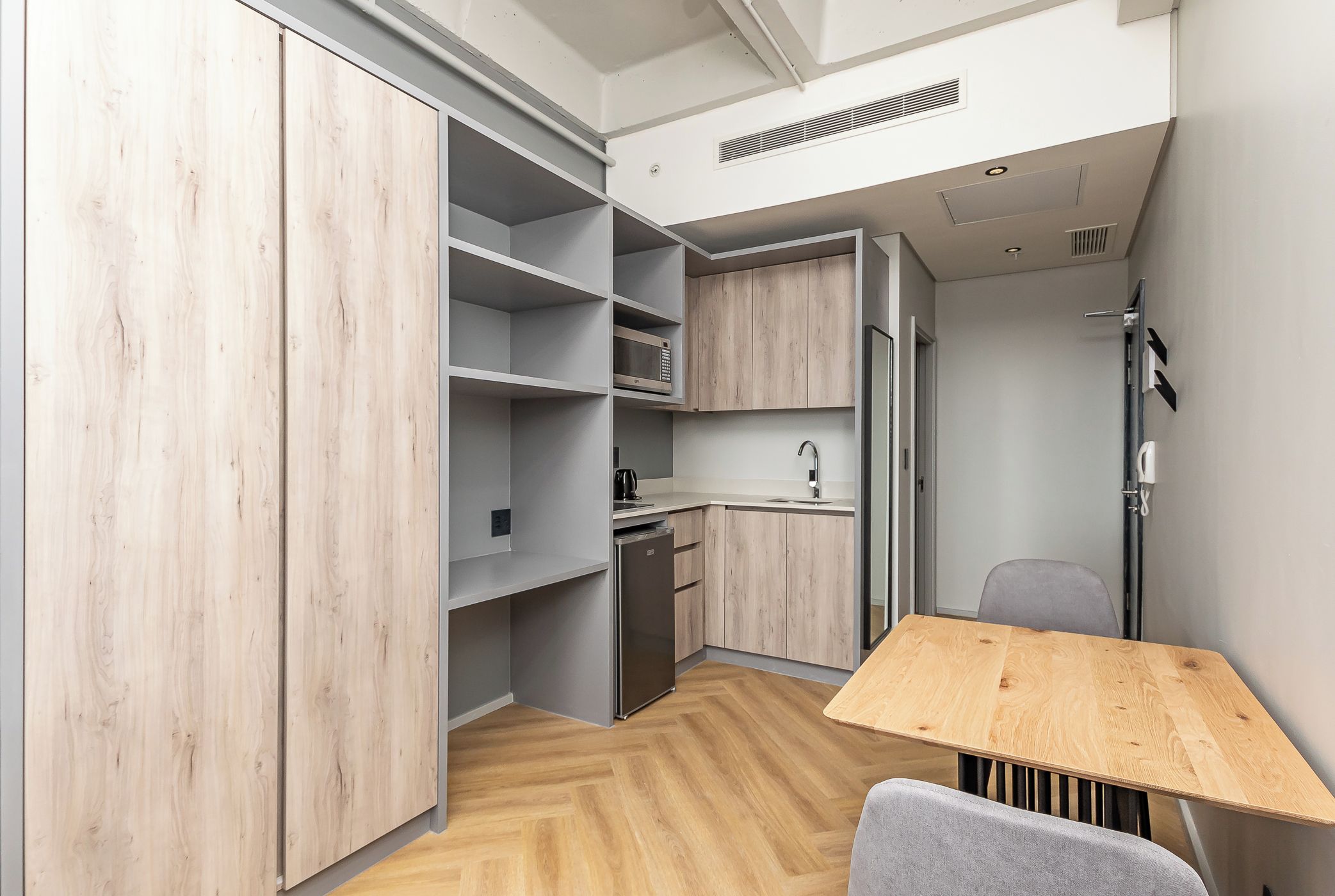 A compact kitchen with a microwave, sink, and stainless steel refrigerator.