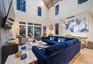 A spacious living area with a sectional sofa, a coffee table, and a large abstract painting on the wall.