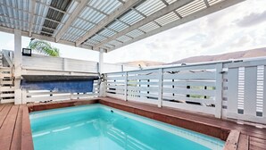 Ein Hallenbad mit Holzboden, weißen Geländern und einem überdachten Bereich mit Metallveranda.