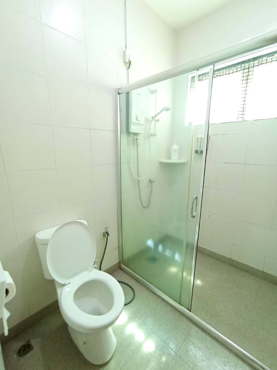 Een badkamer met een toilet, een douchecabine en een witte betegelde muur.