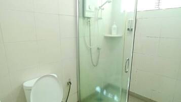 Een badkamer met een toilet, een douchecabine en een witte betegelde muur.