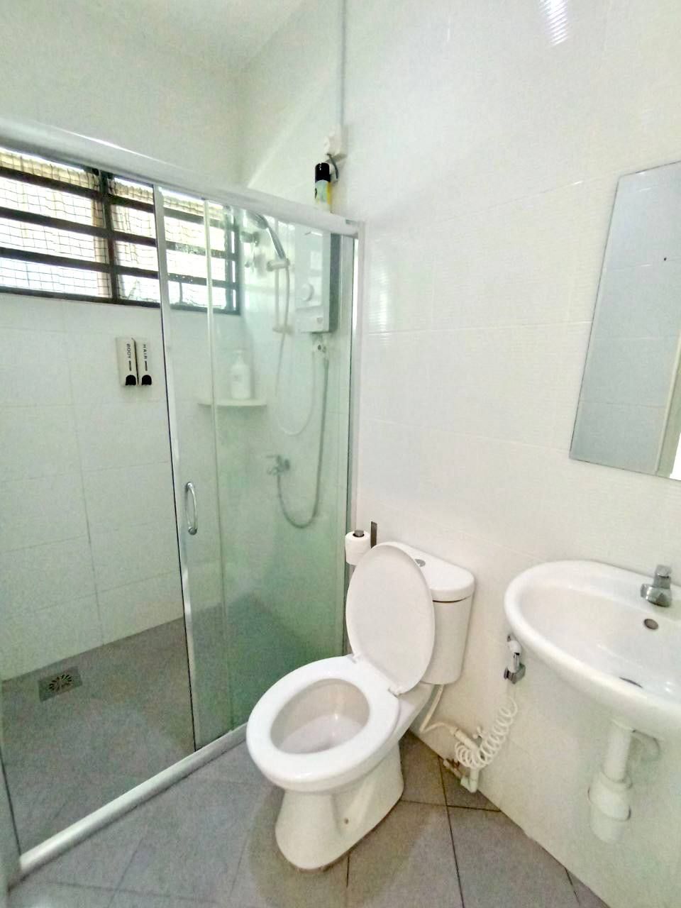 Un baño con ducha de vidrio, inodoro y lavamanos.