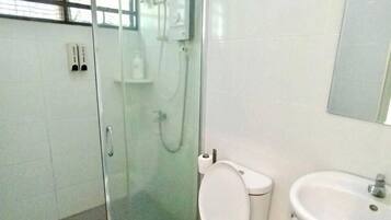 Un baño con ducha de vidrio, inodoro y lavamanos.
