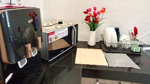 A kitchen with a microwave, a dish rack, and a vase with flowers. - Tropical Livings Meru Ipoh Homestay (Ipoh)