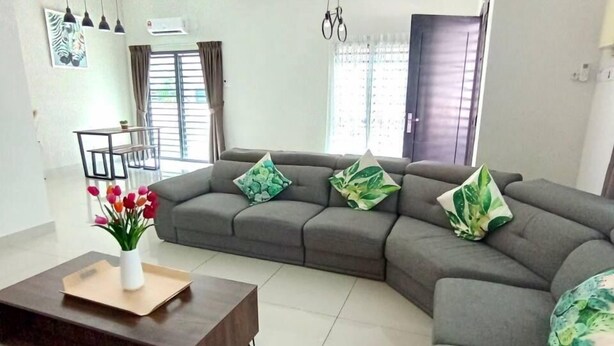 A modern living room with a sectional sofa, a coffee table, and a ceiling fan. - Tropical Livings Meru Ipoh Homestay (Ipoh)